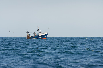 Small fishing boat sailing in an open Mediterranean sea, close-up. A view from the yacht. Leisure activity, sport and recreation, food industry, traditional craft, environmental damage concepts