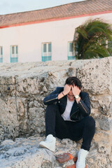 Portrait of a stressed young man looking depressed sitting outdoors.