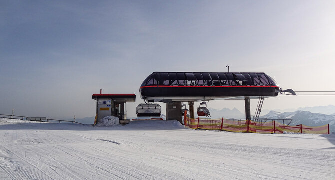 Sesselift Bergstation im Winter, mit Piste und Zaun im Vordergrund.