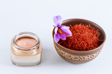 Obraz na płótnie Canvas Saffron stamens in a ceramic bowl and cosmetic cream on a white background.