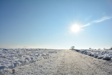 Snow-covered road in the country  with sun