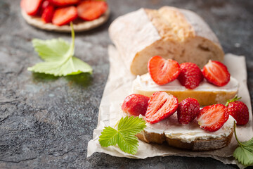 Strawberries sandwiches with cream cheese and on paper, gray background