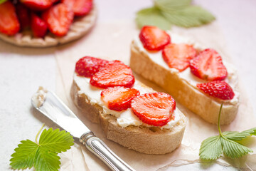 Strawberries sandwiches with cream cheese and on paper, light background
