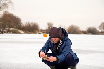 Fototapeta na wymiar Winter fishing. Fisherman on the background of a frozen lake. Close up