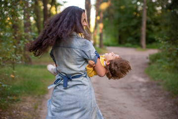 young woman plays with toddler girl in yellow in park