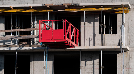 Unloading platform (construction outrigger) to transport materials, equipment at the construction site of an apartment block. High rise block of flats or residential tower houses under construction.