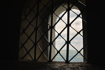 Sillhouette of and old window in Ostrog Monastery church. Monastery against the mountain, build inside the rock. Closeup of window with bars.