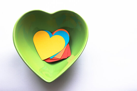There are colorful heart-shaped papers in a heart-shaped bowl. be fed with love. Growing up with love. Eating love. Abstract expressive concept photo.