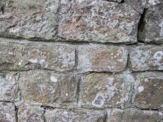 Obraz premium Hilly stone wall with cobblestones. Grungy background with grainy surface.