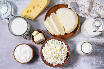 Fototapeta na wymiar Set of different dairy products (milk, sour cream, cottage cheese, yogurt and butter) on a light stone countertop. Top view flat lay.