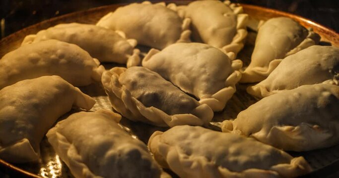 Time lapse of a dozen empanadas being baked inside an oven.