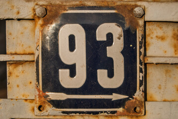 Weathered grunge square metal enameled plate of number of street address with number 93