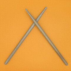 Crossed percussion drumsticks on an orange background.