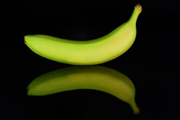 A yellow banana is reflected against a dark background