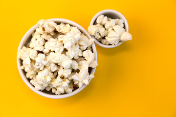 Two bowls of popcorn on a yellow background.