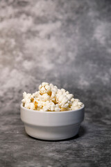Bowl with popcorn on a grey background
