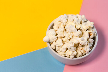 Bowl with popcorn on a yellow, blue and pink background