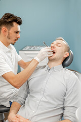 Obraz na płótnie Canvas Dentist adjusting dental braces during orthodontic treatment for the young male patient. High quality photo