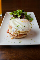 Croque madame or monsieur. Breakfast or brunch favorite: toast, with fried eggs, ham, cheese, and hollandaise sauce. Served with potato hash. Classic French bistro or American restaurant entree.