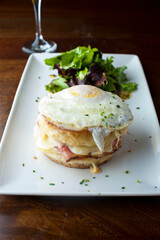 Croque madame or monsieur. Breakfast or brunch favorite: toast, with fried eggs, ham, cheese, and hollandaise sauce. Served with potato hash. Classic French bistro or American restaurant entree.
