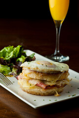 Croque madame or monsieur. Breakfast or brunch favorite: toast, with fried eggs, ham, cheese, and hollandaise sauce. Served with potato hash. Classic French bistro or American restaurant entree.