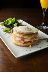 Croque madame or monsieur. Breakfast or brunch favorite: toast, with fried eggs, ham, cheese, and hollandaise sauce. Served with potato hash. Classic French bistro or American restaurant entree.