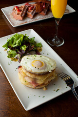 Croque madame or monsieur. Breakfast or brunch favorite: toast, with fried eggs, ham, cheese, and hollandaise sauce. Served with potato hash. Classic French bistro or American restaurant entree.