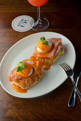 Eggs Benedict. Traditional classical American diner or French Bistro brunch item. Homemade Hollandaise sauce drizzled over a poached egg, country ham on top of a toasted English muffin.  