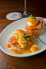 Eggs Benedict. Traditional classical American diner or French Bistro brunch item. Homemade Hollandaise sauce drizzled over a poached egg, country ham on top of a toasted English muffin.  