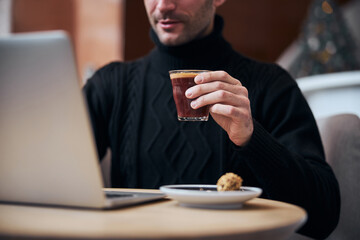 Businessman drinking coffee and working online in lobby