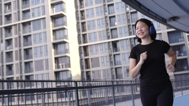 Happy Asian woman wearing sportswear jogging indoors. And good physical health. Workout by running burn excess fat. Stadium in cityscape. Health care concept