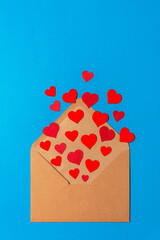 offener Briefumschlag aus dem rote papierherzen kommen auf blauem hintergrund high angle view