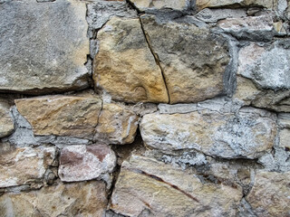 Large cracked boulders. The texture of a destroyed stone wall.