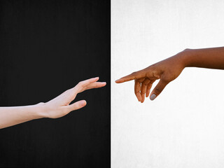 Friendship and racial respect concept with black and white hands reaching towards each other on black and white background - obrazy, fototapety, plakaty