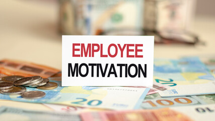 On the table are bills, a bundle of dollars and a sign on which it is written - EMPLOYEE MOTIVATION. Finance and economics concept.