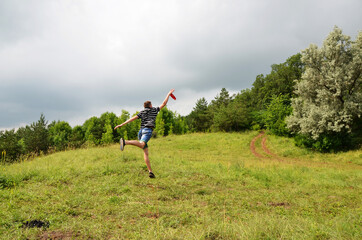 A teenager in a green meadow catches a flying disc in a jump