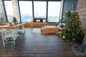 On the eve of the holiday, the interior of the country house is decorated with a New Year tree. large spacious light room decorated with wood with simple wood furniture