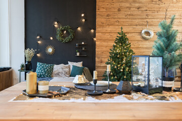 On the eve of the holiday, the interior of the country house is decorated with a New Year tree. large spacious light room decorated with wood with simple wood furniture