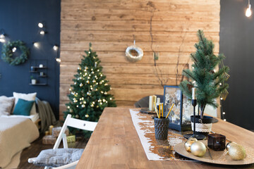 On the eve of the holiday, the interior of the country house is decorated with a New Year tree. large spacious light room decorated with wood with simple wood furniture