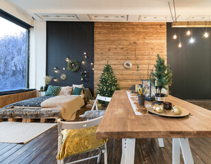 On the eve of the holiday, the interior of the country house is decorated with a New Year tree. large spacious light room decorated with wood with simple wood furniture