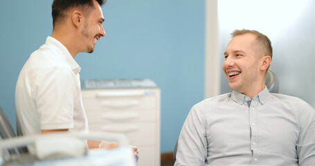Happy male patient a doctor during a regular orthodontic visit at the dental office. Happy dental treatment concept. 4k video screenshot, please use in small size