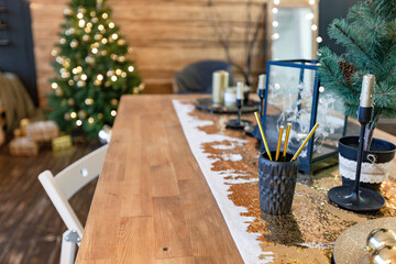 On the eve of the holiday, the interior of the country house is decorated with a New Year tree. large spacious light room decorated with wood with simple wood furniture