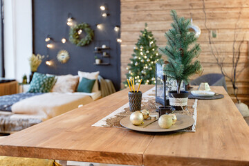 On the eve of the holiday, the interior of the country house is decorated with a New Year tree. large spacious light room decorated with wood with simple wood furniture