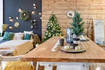 On the eve of the holiday, the interior of the country house is decorated with a New Year tree. large spacious light room decorated with wood with simple wood furniture