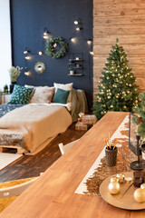 On the eve of the holiday, the interior of the country house is decorated with a New Year tree. large spacious light room decorated with wood with simple wood furniture