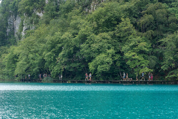 Plitvice, Croatia - Aug 11, 2020: Tourists walk by aqua color lake