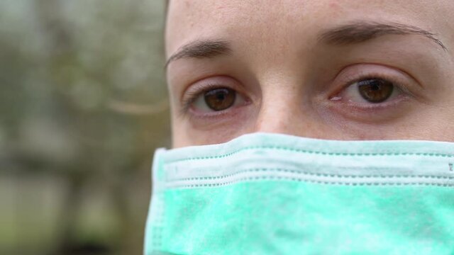 Deep sadness in woman's eyes wearing protective medical mask during coronavirus infection and looking on camera. Female eyes full of tears, fear of future, struggle between human and biological weapon