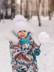 Little cute girl holds a snowball in winter in the park