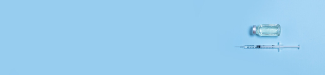 Syringe with medicine from glass vial on light blue background. Vaccination against influenza, covid 19, measles, coronavirus disease.