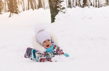 Fototapeta na wymiar Little baby girl lies in the snow on a winter day